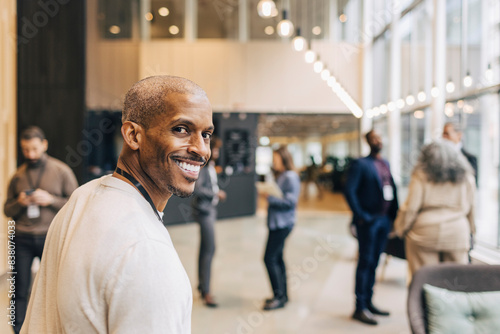 Portrait of smiling male entrepreneur looking over shoulder at convention center photo