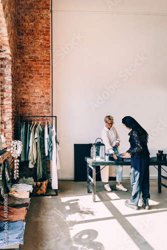 Female customer paying via credit card at checkout in clothing store photo