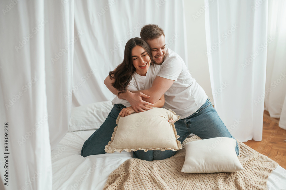 Soft pillows are in hands, playing. Young couple are together at home Soft pillows are in hands, playing. Young couple are together at home