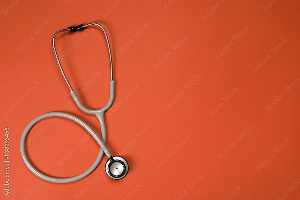 Stethoscope on crimson background, top view. Space for text Stethoscope on crimson background, top view. Space for text