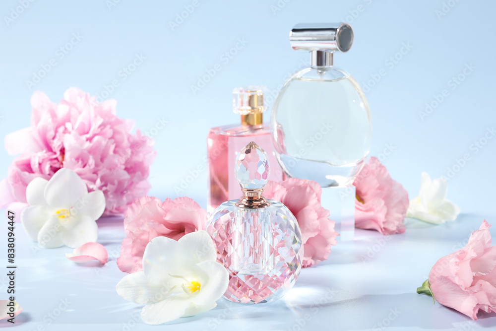 Bottles of luxury perfumes and floral decor on light blue background Bottles of luxury perfumes and floral decor on light blue background