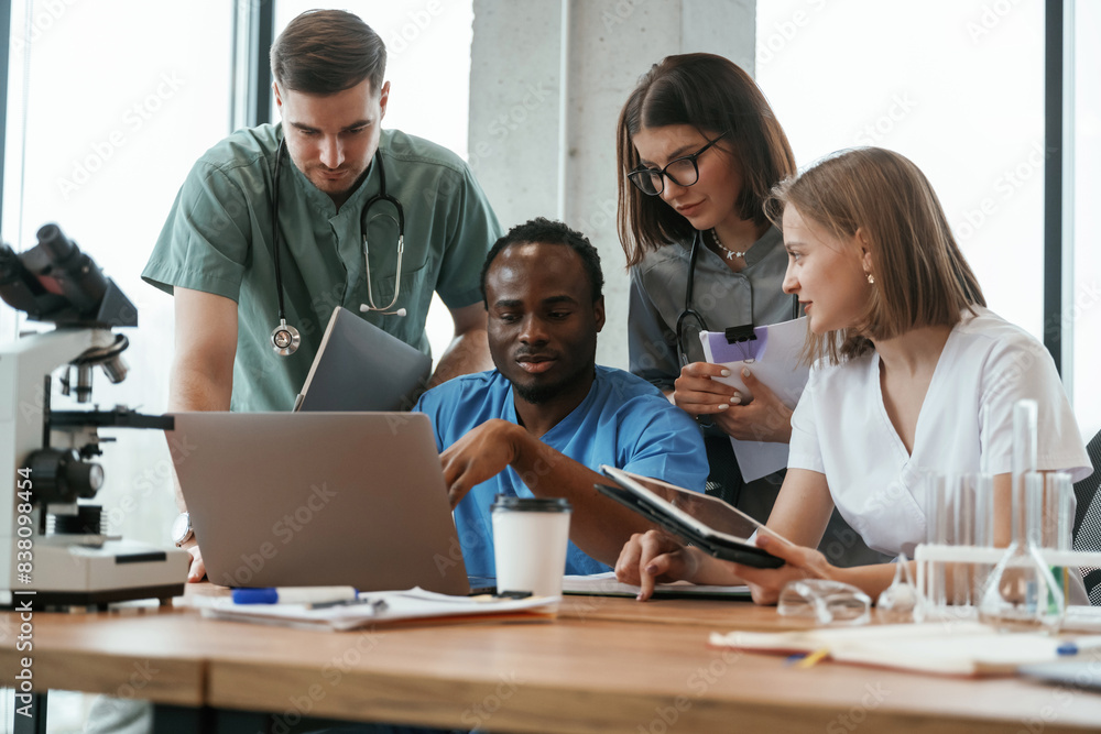 Reading information from laptop. Group of doctors are together indoors Reading information from laptop. Group of doctors are together indoors