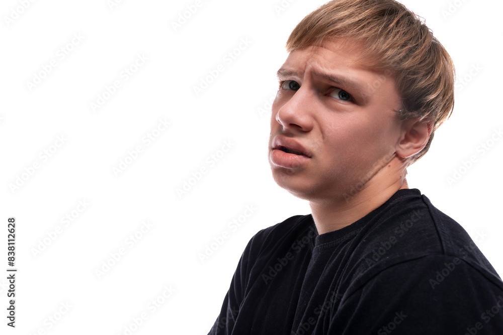 Upset fair-haired teenager guy in a black T-shirt on a white background Upset fair-haired teenager guy in a black T-shirt on a white background