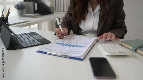 A woman is sitting at a desk with a laptop and a cell phone