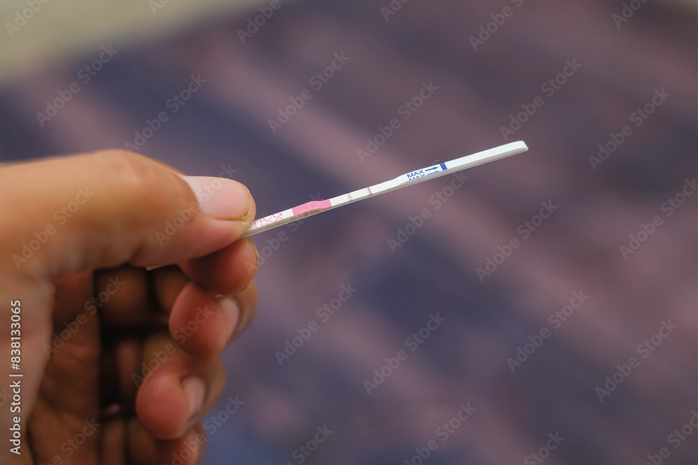 Woman hand holding positive pregnancy test strips on wood background Woman hand holding positive pregnancy test strips on wood background
