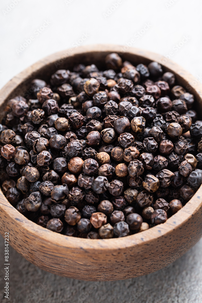 Indian spice black pepper in wooden bowl close-up on gray background Indian spice black pepper in wooden bowl close-up on gray background