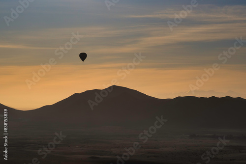 A single hot air balloon, sihouetted against the sun rise, as it floats above Morocco's Atlas mountians photo