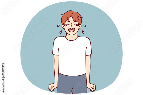 Crying teenage boy stands clenching fists nervous after receiving reprimand from parents associated with poor grades at school. Teenage child crying due to psychological disorder or lack of toys