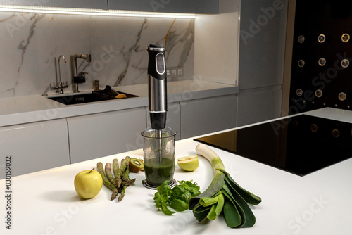Electric immersion blender on kitchen table with green vegetables