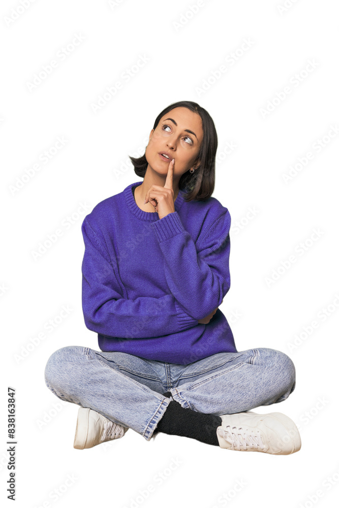 Young Caucasian woman sitting on floor looking sideways with doubtful and skeptical expression. Young Caucasian woman sitting on floor looking sideways with doubtful and skeptical expression.