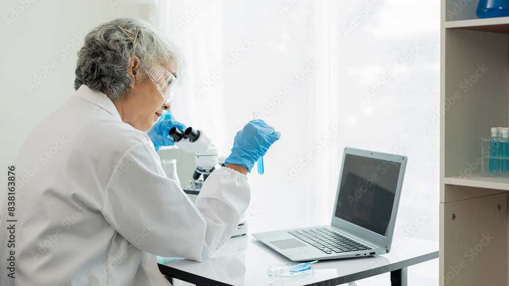 Two senior Asian scientists working in a laboratory are scientists researching biology and chemistry. Couple wearing glasses and looking into a microscope, medical concept Two senior Asian scientists working in a laboratory are scientists researching biology and chemistry. Couple wearing glasses and looking into a microscope, medical concept