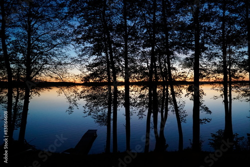 Fototapeta Naklejka Na Ścianę i Meble -  Sunset over lake with trees at shore
