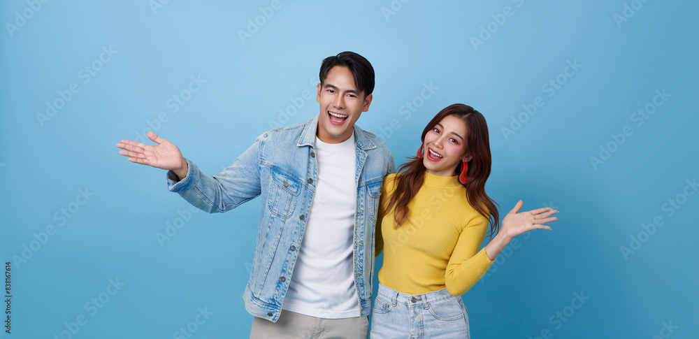 Happy Asian teen couple presenting or showing open hand palm with for product isolated on blue studio copy space background.