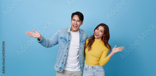 Fotografia Happy Asian teen couple presenting or showing open hand palm with for product isolated on blue studio copy space background