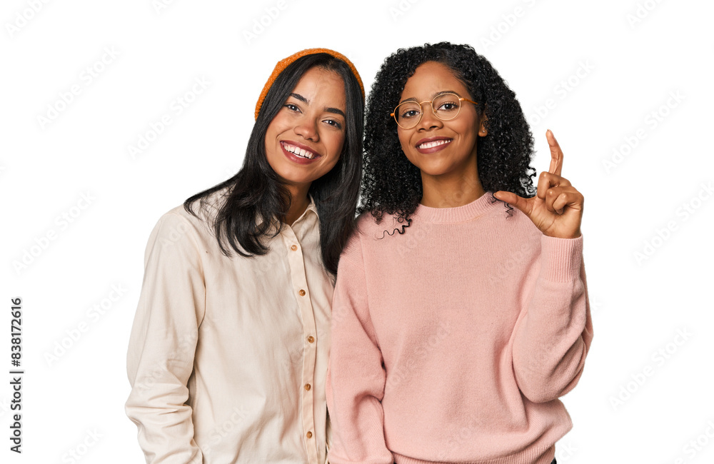 Young Latin friends together in studio holding something little with forefingers, smiling and confident. Young Latin friends together in studio holding something little with forefingers, smiling and confident.