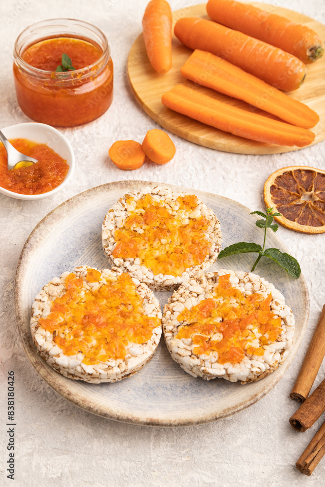 Carrot jam with puffed rice cakes on gray concrete. Side view. Carrot jam with puffed rice cakes on gray concrete. Side view.
