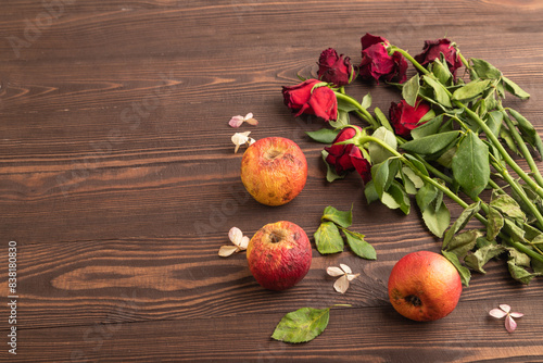 Bilde på lerret Withered, decaying, roses flowers and apples on brown wooden background