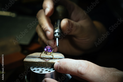 Close up of a goldsmith's hand making a gold or silver ring or a diamond using goldsmith's tools. For this work it takes precision and patience. Concept of: tradition, luxury, jewelry.