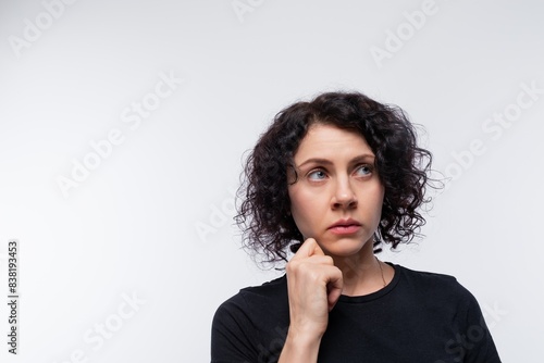 Cute curly European woman in a black T-shirt against a studio background