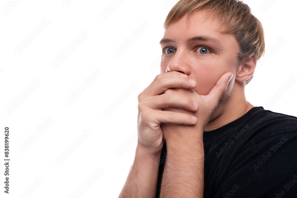 Shocked teenage guy with blond hair covered his mouth with his hands Shocked teenage guy with blond hair covered his mouth with his hands