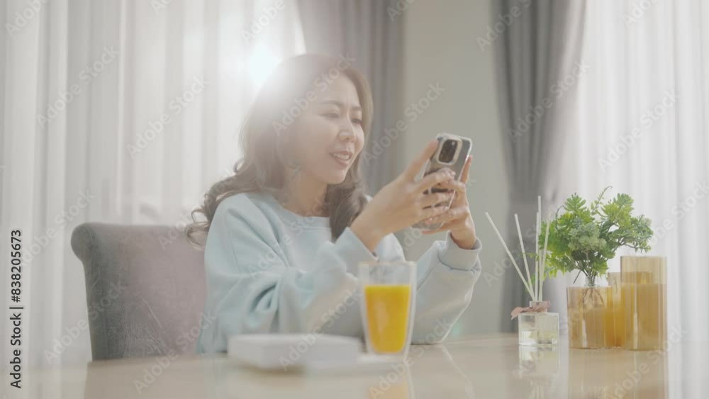 Women are playing with their mobile phones on the sofa and the dining table and drinking coffee or orange juice at the same time. Women are playing with their mobile phones on the sofa and the dining table and drinking coffee or orange juice at the same time.