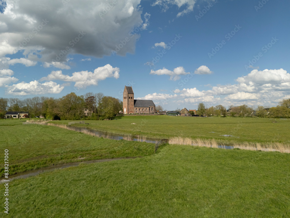 Aerial View: Church in Wanswert, Friesland, Netherlands with Beautiful Cloudy Sky Aerial View: Church in Wanswert, Friesland, Netherlands with Beautiful Cloudy Sky