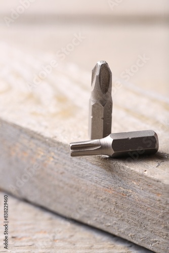 Different screwdriver bits on wooden table, closeup