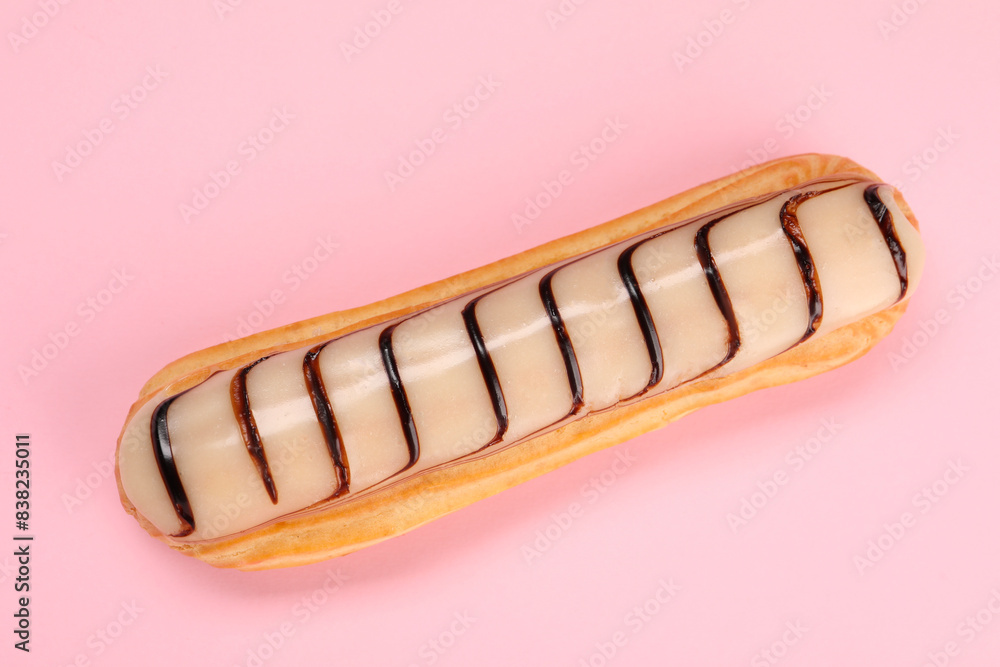 Delicious eclair covered with glaze on pink background, top view Delicious eclair covered with glaze on pink background, top view