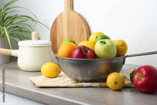 Metal colander with different fruits on countertop in kitchen