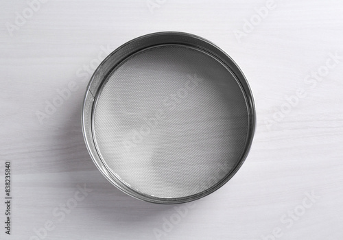 Photos One metal sieve on white wooden table, top view