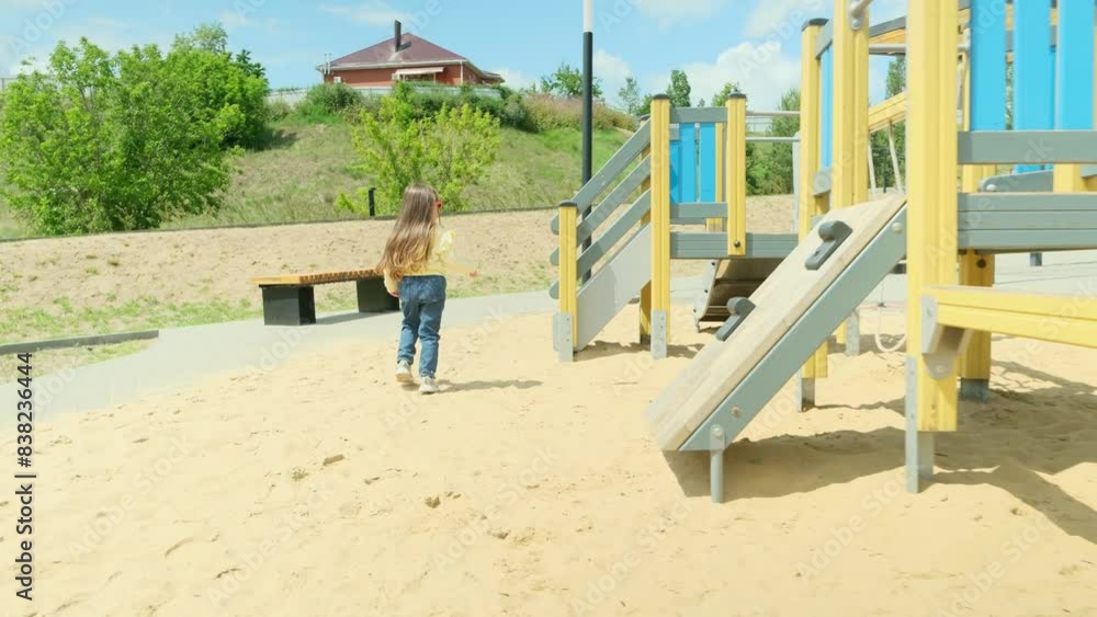 Cute little girl in sunglasses playing on the playground in the park. Summer holiday concept, summer vacation Cute little girl in sunglasses playing on the playground in the park. Summer holiday concept, summer vacation