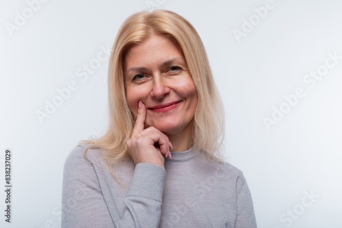 Mature blond woman smiling modestly and sweetly  close-up portrait
