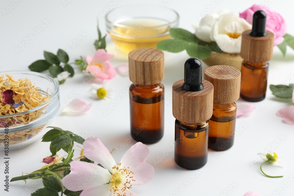 Aromatherapy. Essential oils and flowers on white table Aromatherapy. Essential oils and flowers on white table