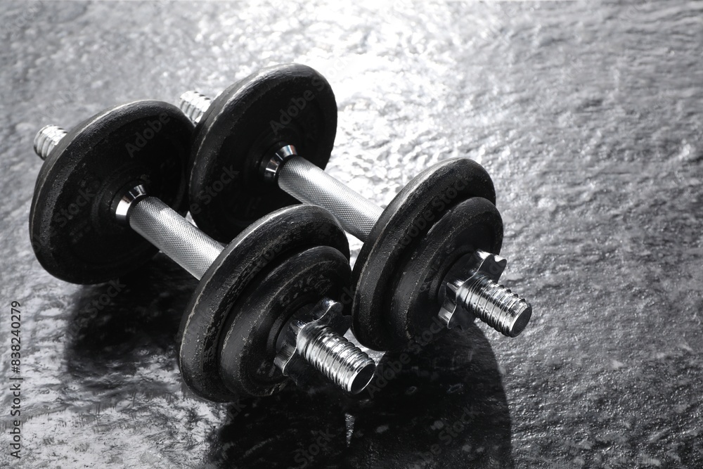 Two barbells on dark textured floor, closeup Two barbells on dark textured floor, closeup