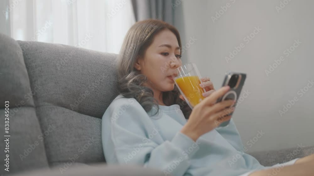 Women are playing with their mobile phones on the sofa and the dining table and drinking coffee or orange juice at the same time. Women are playing with their mobile phones on the sofa and the dining table and drinking coffee or orange juice at the same time.
