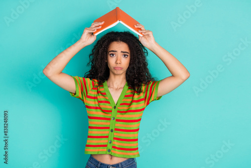 Photo portrait of pretty young girl depressed hold book roof wear trendy striped outfit isolated on aquamarine color background
