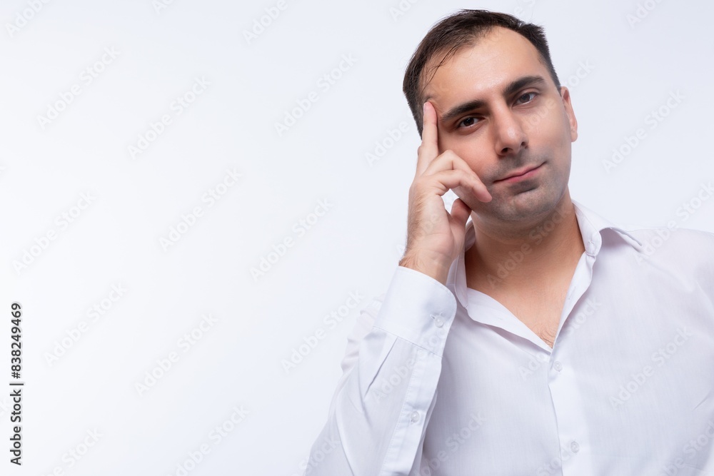 Portrait of a smart European brunette man in a white shirt holding his index finger up