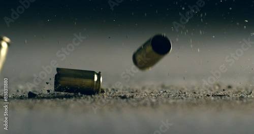 Super slow motion macro of bullet shell casings of machine fire gun falling down on ground with flying gunpowder during training in shooting range. Shooting and Weapons