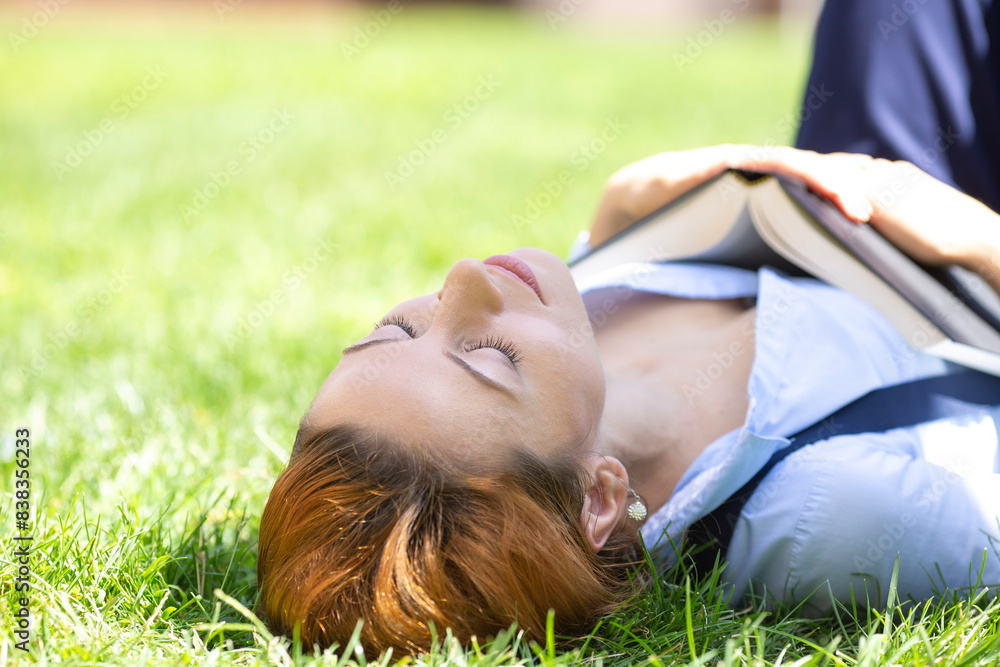 Beautiful girl is relaxing lying on the grass in the garden Beautiful girl is relaxing lying on the grass in the garden