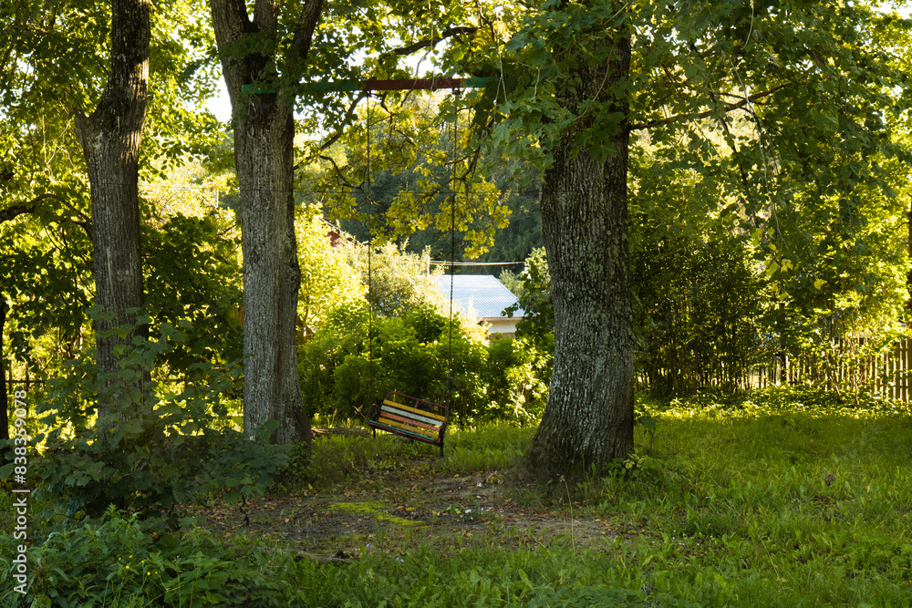 An old swing weighs between two trees. Colorful homemade swing in the park. An old swing weighs between two trees. Colorful homemade swing in the park.