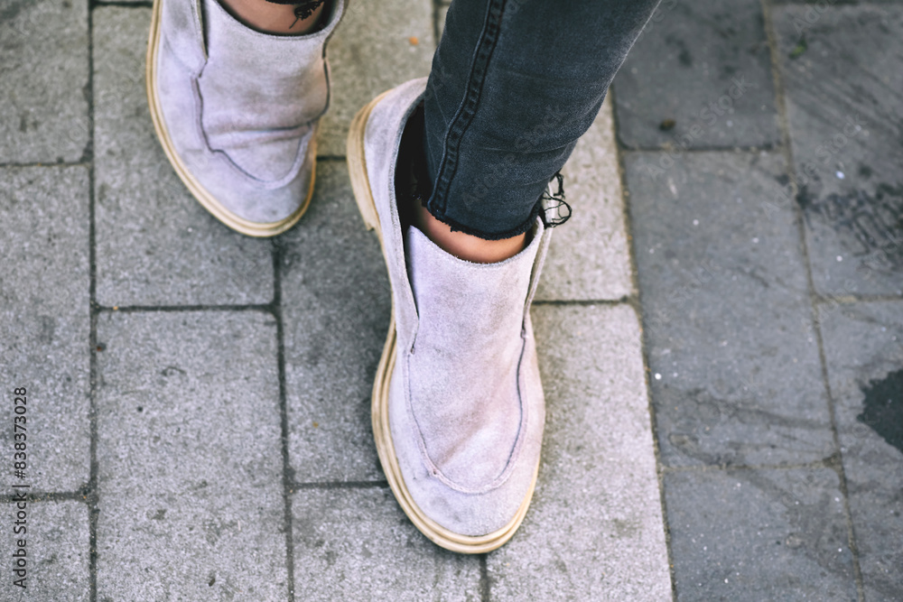 Female legs feet dressed in rag moccasin shoes walking along a tiled pavement Female legs feet dressed in rag moccasin shoes walking along a tiled pavement
