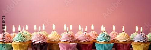 Colorful cupcakes with lit candles are displayed against a pink background  indicating an indoor celebration event marking of joy and celebrating. with free space