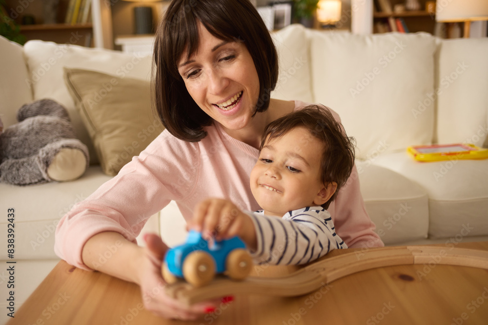 Cute little boy and his mother playing with wooden train at home Cute little boy and his mother playing with wooden train at home