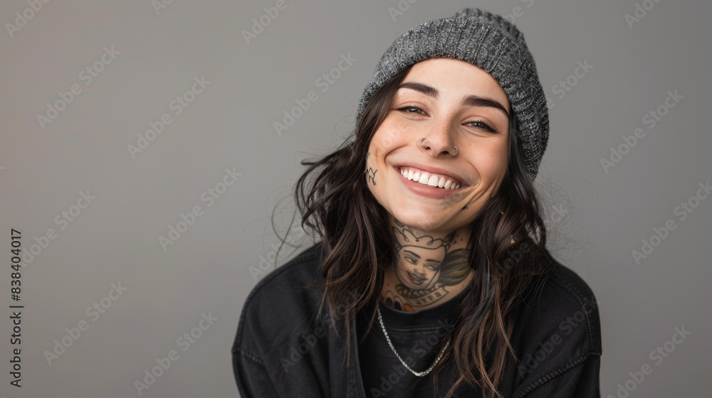 A smiling woman with tattoos on her neck and face, wearing a black beanie, exuding confidence and alternative style.
A smiling woman with tattoos on her neck and face, wearing a black beanie, exuding confidence and alternative style.
