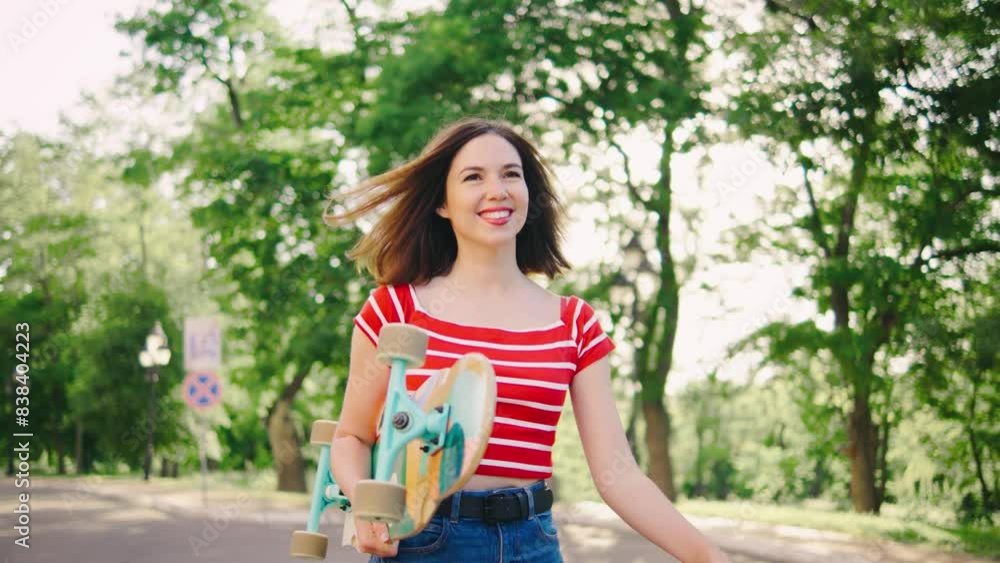 beautiful young woman walks through the park with a skateboard in her hands. The girl is carrying a longboard. The girl is happy and enjoying the moment beautiful young woman walks through the park with a skateboard in her hands. The girl is carrying a longboard. The girl is happy and enjoying the moment