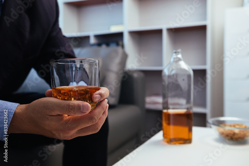 businessman sits and holds glass of liquor in his hand to drink relieve stress after experiencing problems in business. businessman drinking alcohol relieve stress from failed business venture.