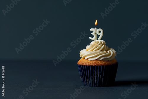 A cupcake topped with a number 39 candle, isolated on a solid dark navy blue background.