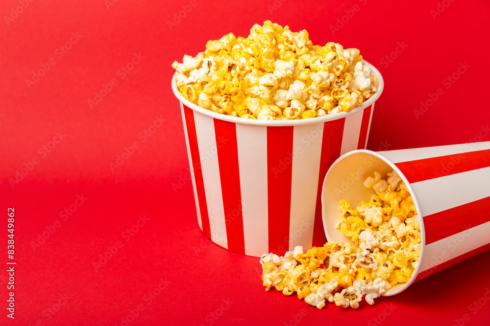 Popcorn box. Red and white striped buckets of popcorn on a red background. Cinema and entertainment concept. Movie night with popcorn. Cheesy popcorn. Delicious appetizer, snack. Place for text. Popcorn box. Red and white striped buckets of popcorn on a red background. Cinema and entertainment concept. Movie night with popcorn. Cheesy popcorn. Delicious appetizer, snack. Place for text.