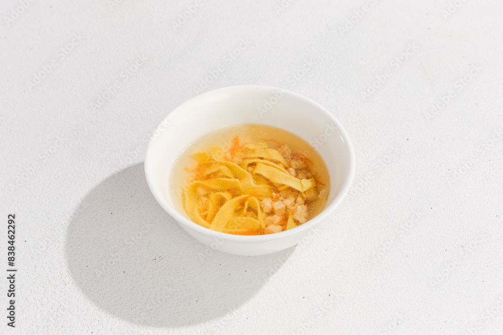 Delicious Homemade Chicken Noodle Soup in White Bowl on Light Background Delicious Homemade Chicken Noodle Soup in White Bowl on Light Background