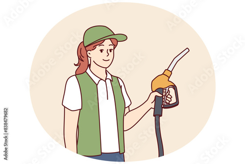 Woman serving customers at refueling station holding nozzles for refilling oil tank. Refueling station employee dressed in service uniform looks at screen with smile making career in fuel industry